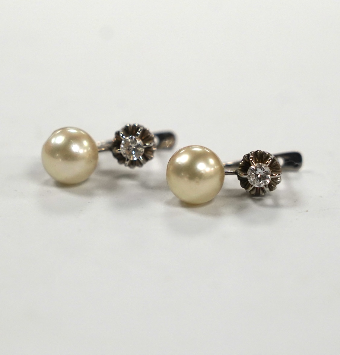 A pair of white metal, single stone cultured pearl and single stone diamond set earrings, 16mm, gross weight 4.8 grams.